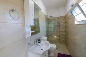 een witte badkamer met een wastafel en een toilet bij Vila Enxhi in Ksamil