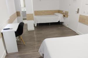 メリダにあるDeluxe Hostels & Suites Meridaのベッド2台、テーブル、椅子が備わる小さな客室です。
