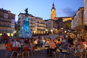 um grupo de pessoas sentadas em cadeiras em uma cidade em La Casa de Los Arquillos em Vitoria-Gasteiz