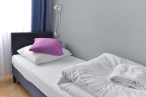 a bed with a purple pillow on top of it at Hotel Elda 2 in Bydgoszcz