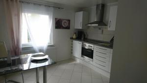 eine Küche mit weißen Schränken, einem Fenster und einem Herd in der Unterkunft Apartment City in Radolfzell am Bodensee