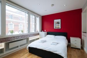 Un dormitorio con una pared roja y una cama en Amazing Studio Flat in Central London. Stylish & Cosy, en Londres