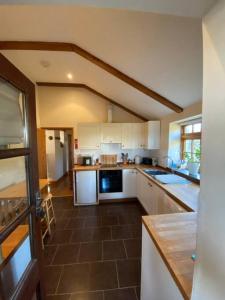 a kitchen with white cabinets and a brown tile floor at Sundance Cottage Sleeps 4 plus 2 in Camelford