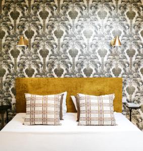 a bed with two pillows in front of a wallpaper at Villa Segur in Bordeaux