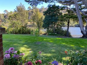 a garden with flowers and a lake in the background at River Front Estate in Huonville