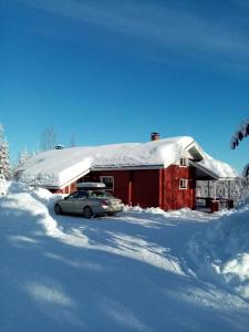 um carro estacionado em frente a um celeiro vermelho com neve em Metsorinne em Kotila