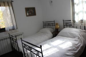 two beds in a bedroom with white sheets at New Bakalov House in Bozhentsi