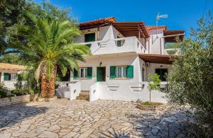 a house with a palm tree in front of it at Olympia Paxos Villas & Apartments in Gaios