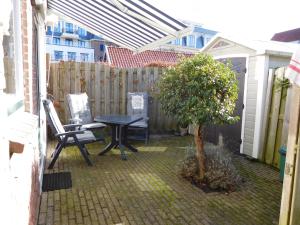 een patio met een tafel en stoelen en een boom bij Wijngaardstraat 7a Domburg in Domburg