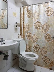 a bathroom with a toilet and a sink and a shower curtain at Casa Tentay in Iloilo City