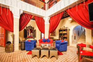 uma sala de estar com cortinas vermelhas e cadeiras azuis em Kasbah Ait Oumghar em Demnat