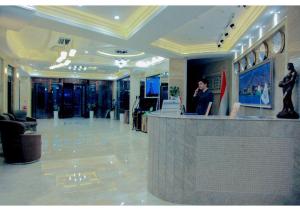 a man standing at a counter in a lobby at Parliament Palace Hotel in Khujand
