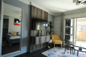a living room with a mirror and a table and a chair at The View - Luxury Apartment in eMalahleni