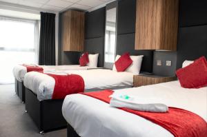 Habitación de hotel con 4 camas con almohadas rojas en Hotel Express Newcastle Gateshead, en Newcastle