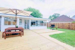 a patio with a bench and an umbrella at Gorgeous Luxury Chalet, New Forest & Coast & in Hordle