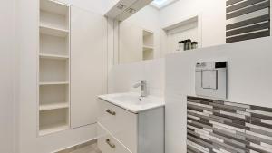 La salle de bains blanche est pourvue d'un lavabo et d'étagères. dans l'établissement Dom & House - Apartments Old Town Ogarna, à Gdańsk