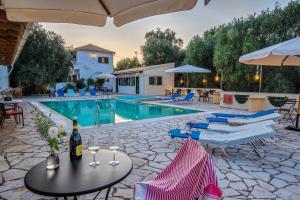 a pool with chairs and a table with a bottle of wine at Olympia Paxos Villas & Apartments in Gaios