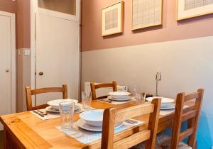 The St Mary's Street Residence في إدنبرة: طاولة طعام مع كراسي وطاولة خشبية مع لوحات