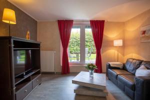 een woonkamer met een bank en een tv bij Frieslandstern - Ferienhof und Hotel in Wangerland
