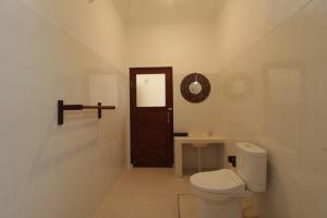 a white bathroom with a toilet and a sink at EKADWI Guesthouse in Gianyar
