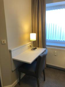 un tavolo con una lampada e una sedia davanti a una finestra di Buskes Hotel Steinförde a Wietze
