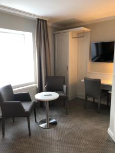 Zimmer mit Stühlen, einem Tisch und einem TV in der Unterkunft Buskes Hotel Steinförde in Wietze