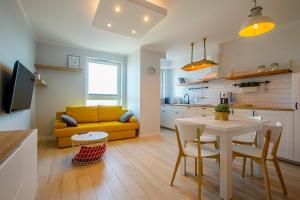 a kitchen and living room with a table and a yellow couch at Grand Apartments - Apartment on the 17th floor with panorama in Gdańsk