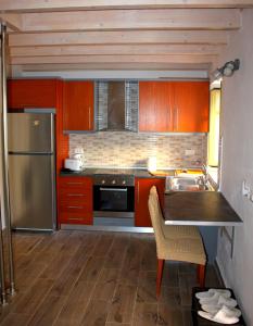 EVANNA HOUSE في سيمي: مطبخ مع خزائن برتقال وثلاجة حديد قابلة للصدأ
