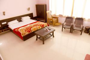 a bedroom with a bed and chairs and a table at Hotel Rani Bagh Resort in Beāwar