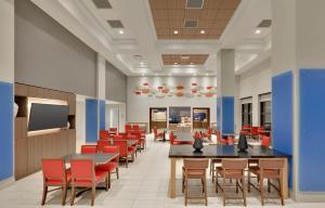 a dining room with tables and red chairs at Holiday Inn Express & Suites Irving Conv Ctr - Las Colinas by IHG in Irving