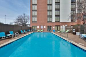 a large swimming pool with chairs and a building at Holiday Inn Express & Suites Irving Conv Ctr - Las Colinas, an IHG Hotel in Irving