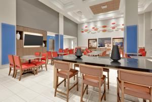 a cafeteria with tables and chairs and a tv at Holiday Inn Express & Suites Irving Conv Ctr - Las Colinas, an IHG Hotel in Irving