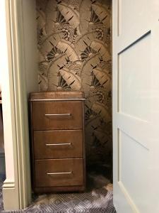 a closet with a dresser and a wall with a wallpaper at The Southern Belle in Brighton & Hove