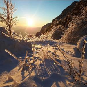 una montaña cubierta de nieve con el sol en el fondo en Hotel Snjezna kuca - Nature Park of Bosnia Herzegovina, en Mostar