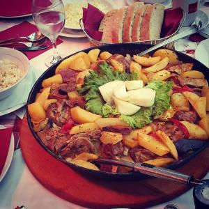 un plato de comida con carne y verduras en una mesa en Hotel Snjezna kuca - Nature Park of Bosnia Herzegovina, en Mostar
