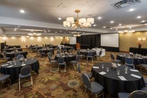 a banquet hall with tables and chairs and a screen at Amenida Residences, Calgary in Calgary