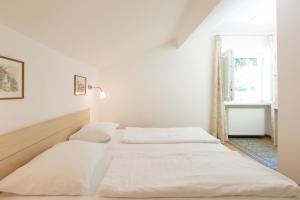 two beds in a white room with a window at Appartements Martinsheim in Tirolo +20 photos
