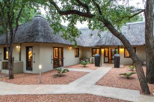 uma casa com telhado de palha e um pátio em Kingly Bush Villa em Phalaborwa