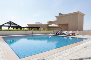 a swimming pool with two chairs and a building at Staycae Holiday Homes - Suburbia, Jebel Ali in Dubai