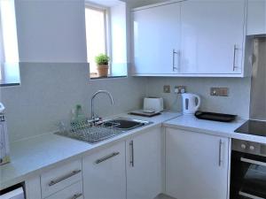 a kitchen with white cabinets and a sink at Heron's View in Ruthin