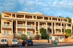 a large building with cars parked in front of it at Opción Roulette de Paya Hotels in Es Pujols