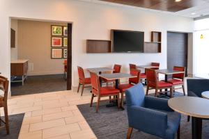 a waiting room with tables and chairs and a flat screen tv at Holiday Inn Express & Suites - Southgate - Detroit Area by IHG in Southgate
