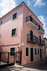 a pink building with balconies and a fence at Maxis apartment 4 in Koroni +2 photos
