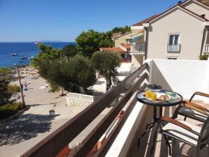 a table on a balcony with a view of a beach at Seaside stay Rošić in Ivan Dolac