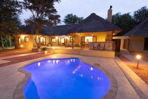a house with a blue pool in front of a house at Kingly Bush Villa in Phalaborwa