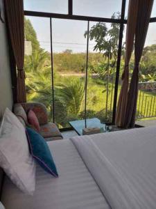 een slaapkamer met een bed en een groot raam bij Plernsalaya resort in Salaya
