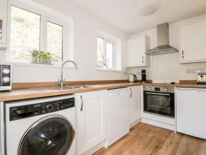 a kitchen with white cabinets and a washer and dryer at Avalon in St. Agnes 