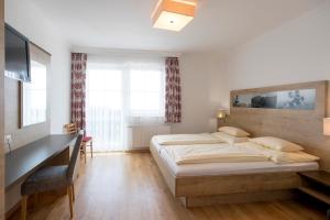 a bedroom with a bed and a desk and a television at Hotel-Restaurant Planaihof in Schladming