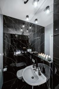 ein schwarz gefliestes Bad mit einem Waschbecken und einem Spiegel in der Unterkunft Słowackiego Apartments in Krakau