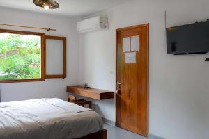 a bedroom with a bed and a television and a window at SATRANA HOTEL TAMATAVE in Toamasina